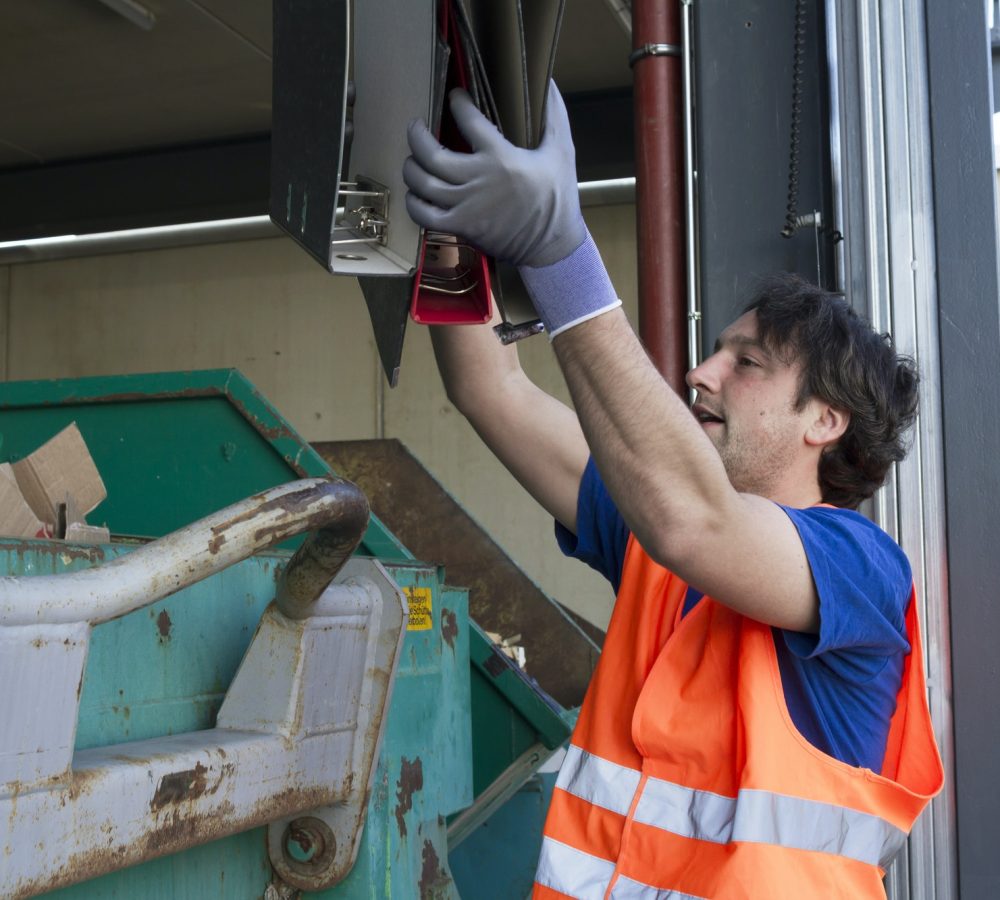 worker-at-a-waste-container-throwing-away-folders.jpg worker-at-a-waste-container-throwing-away-folders.jpg